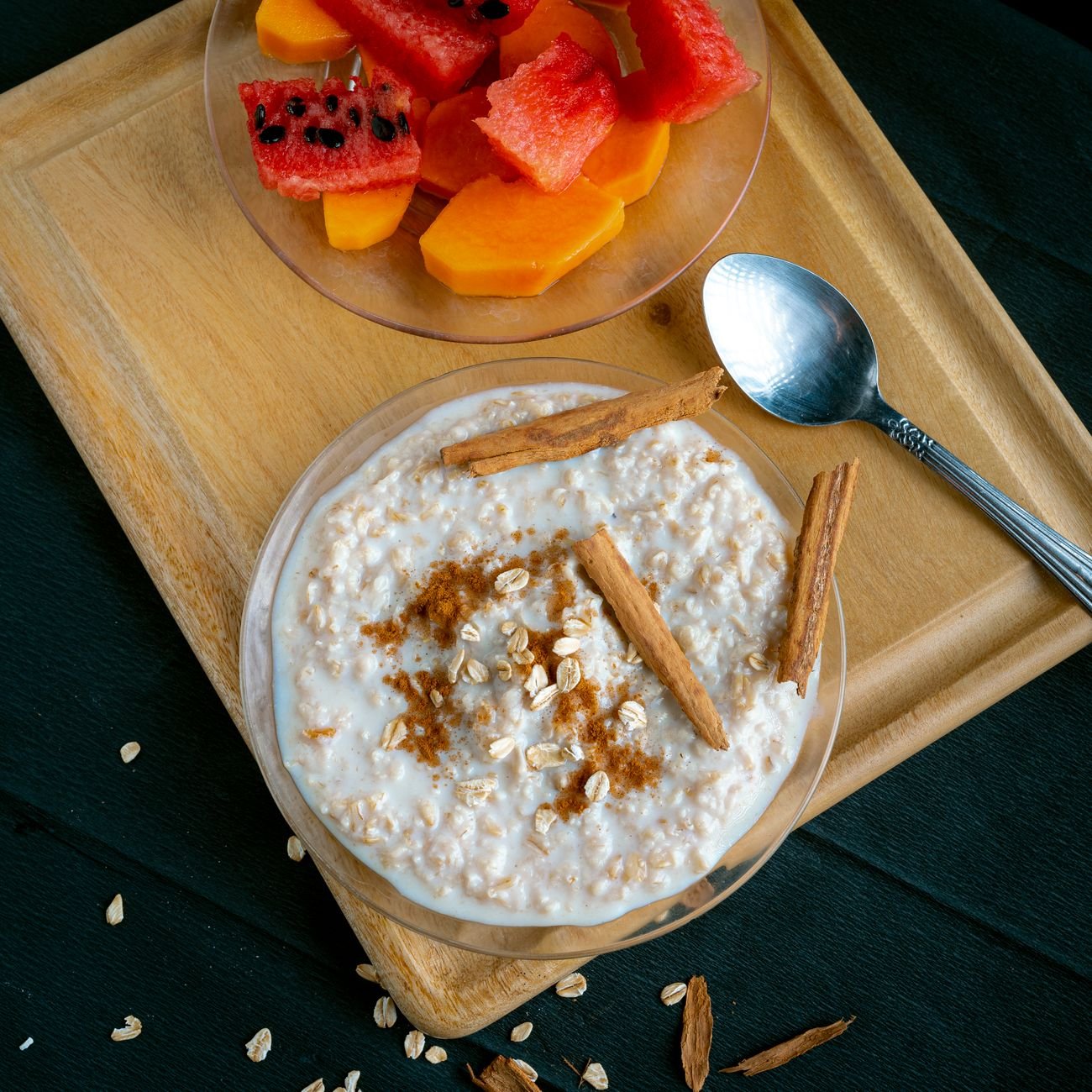 A vibrant breakfast scene featuring cinnamon oatmeal and fresh fruit slices on a wooden tray.