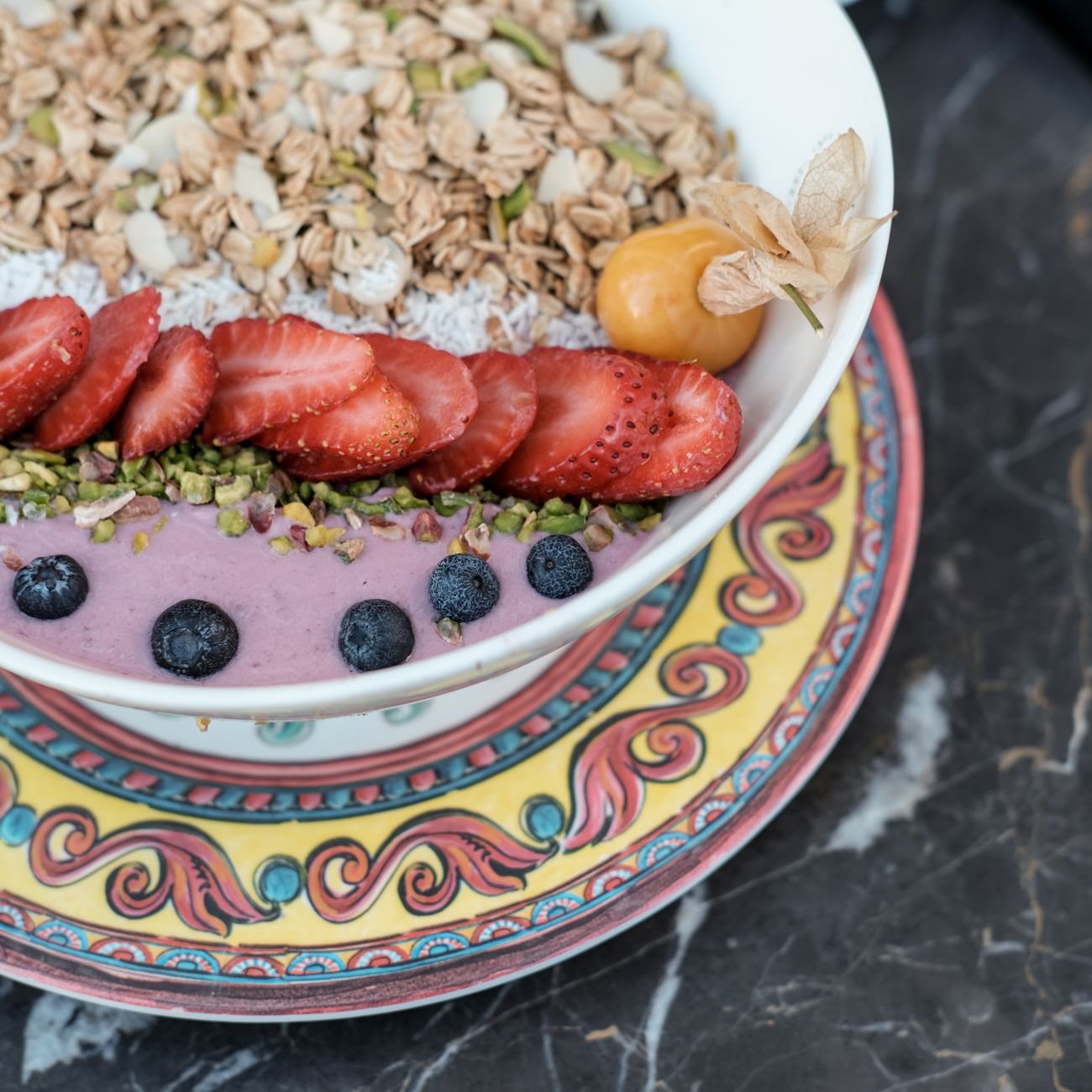 Delicious healthy breakfast bowl featuring fresh berries, granola, and exotic fruits on a decorative plate.